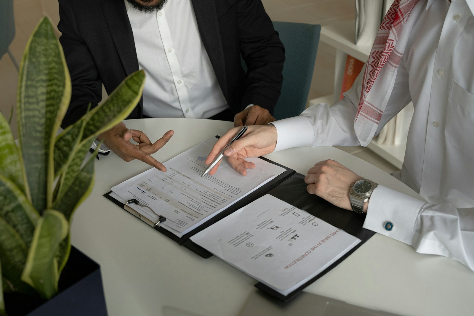 Dos personas revisando y firmando documentos en una mesa de negociación