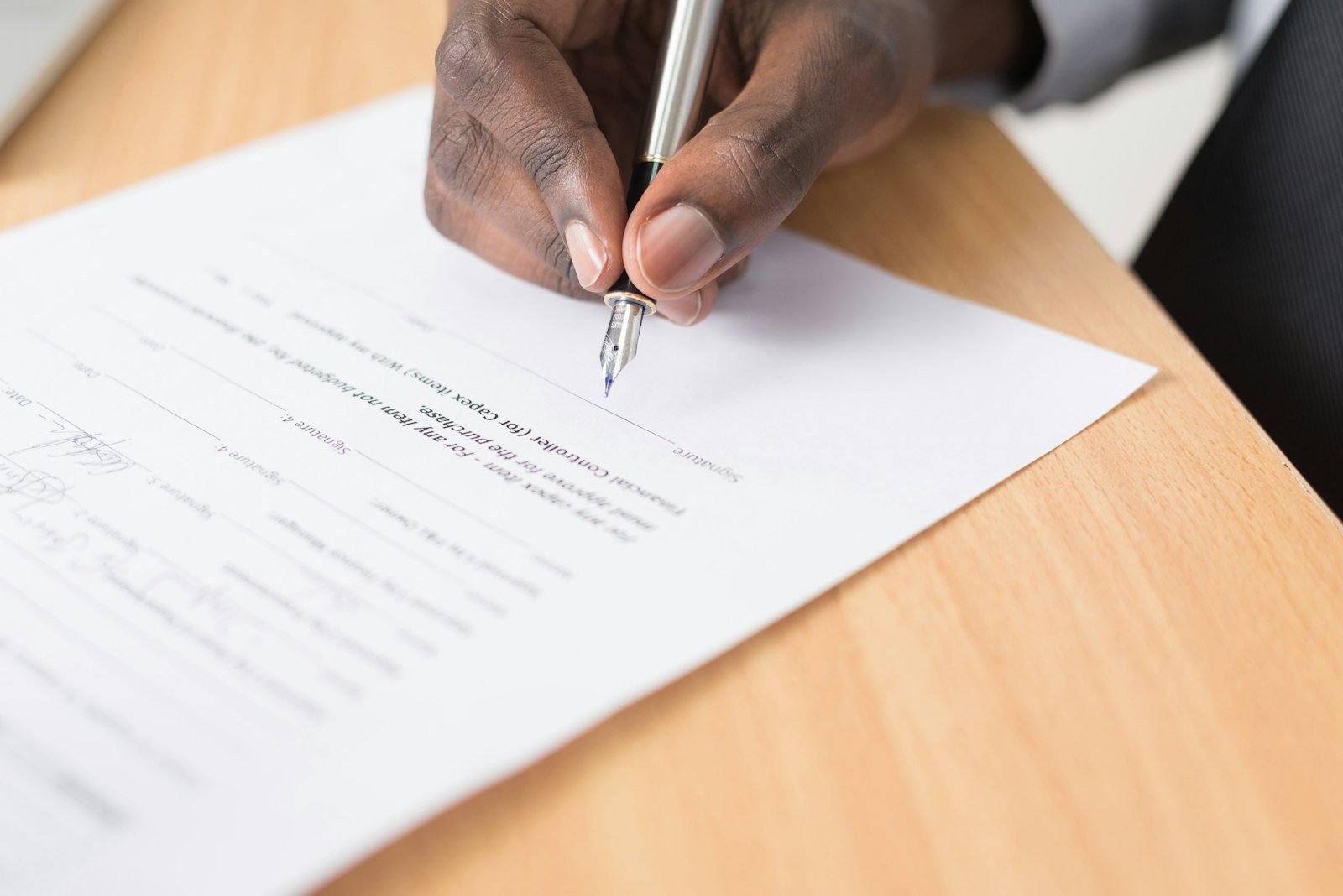 Persona firmando un documento sobre un escritorio
