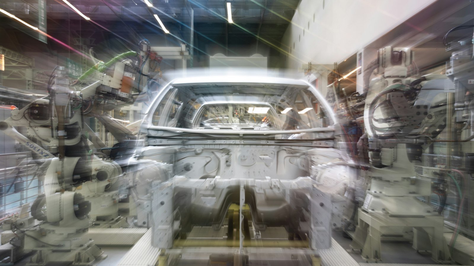 Línea de ensamble automotriz con brazos robóticos y carrocería de un vehículo
