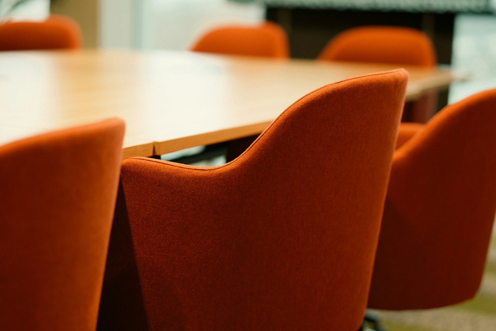 Sala de juntas con sillas alrededor de una mesa de madera, lista para una negociación
