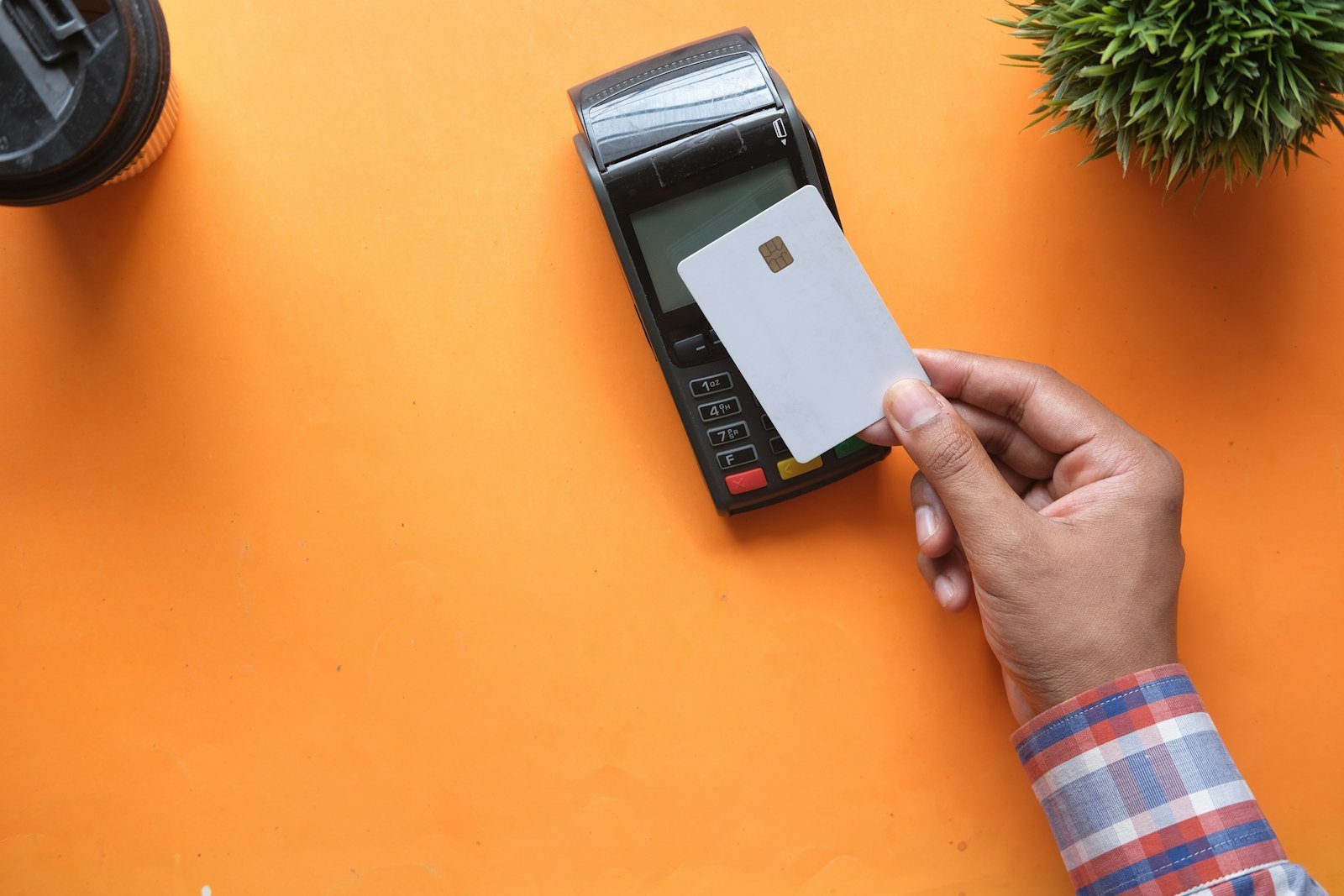 Tarjeta bancaria sin marcas junto a una terminal de pago, pago de nómina por medios electrónicos