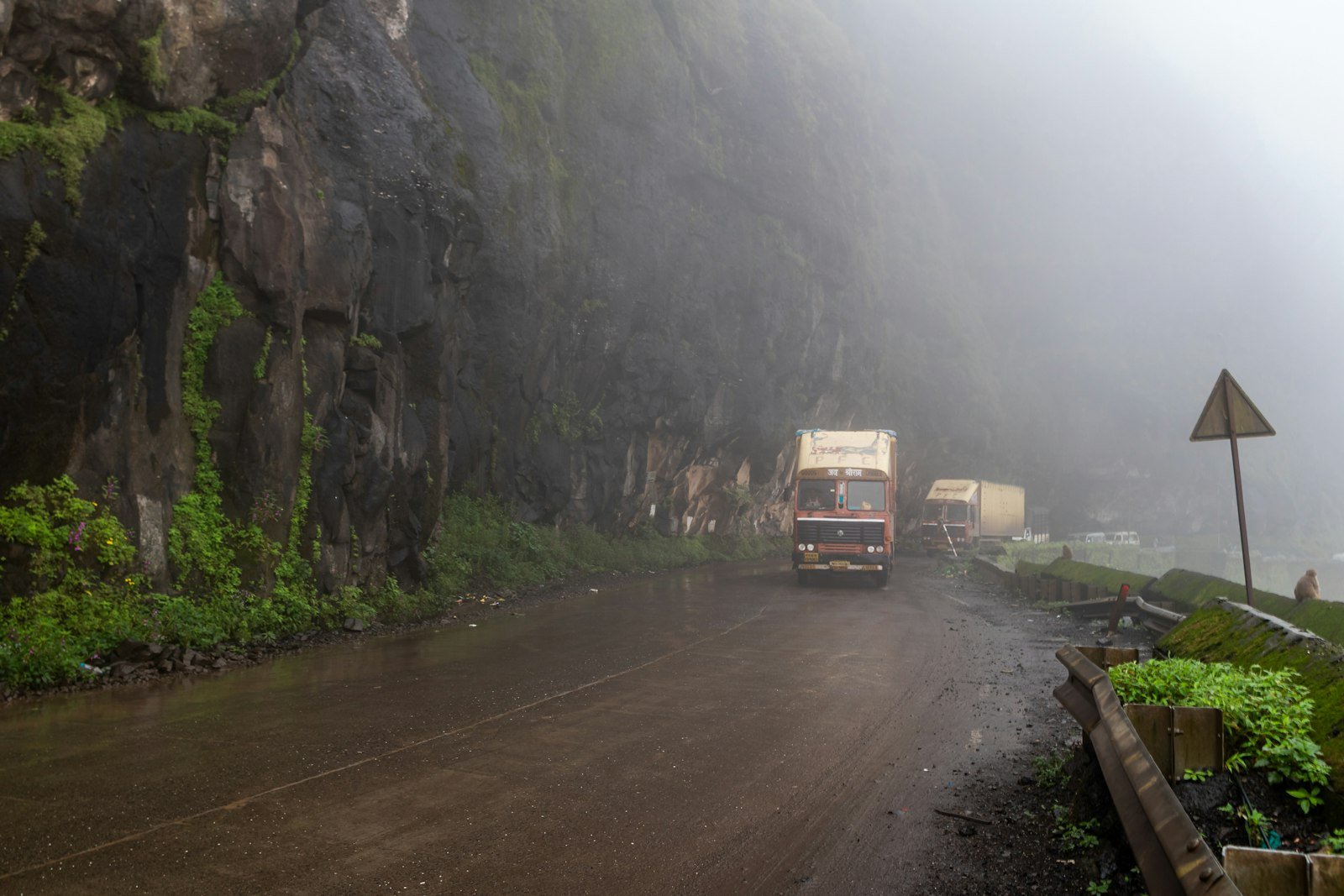 Camión de carga circulando por una carretera húmeda entre neblina