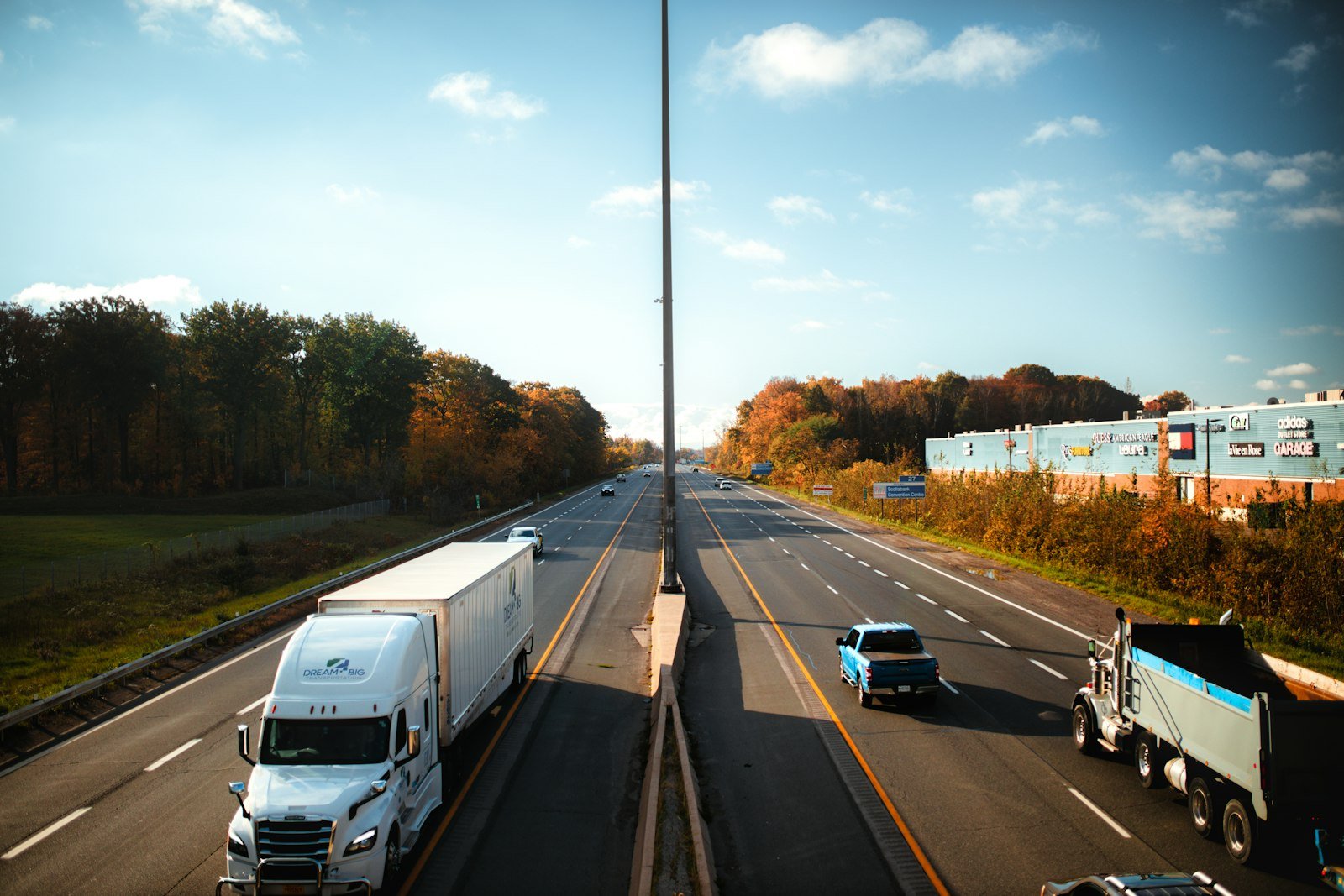 Autopista con tráfico intenso de vehículos y camiones junto a un bosque