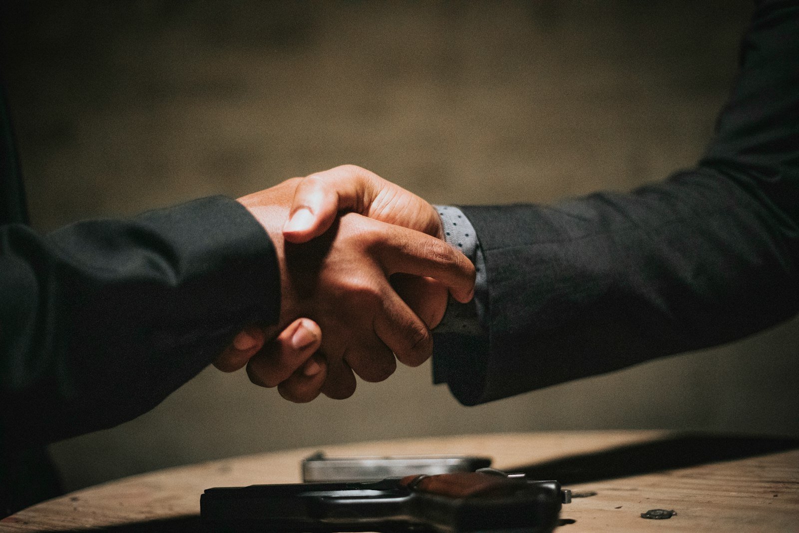 Dos personas se dan la mano sobre una mesa de madera al cerrar una negociación salarial