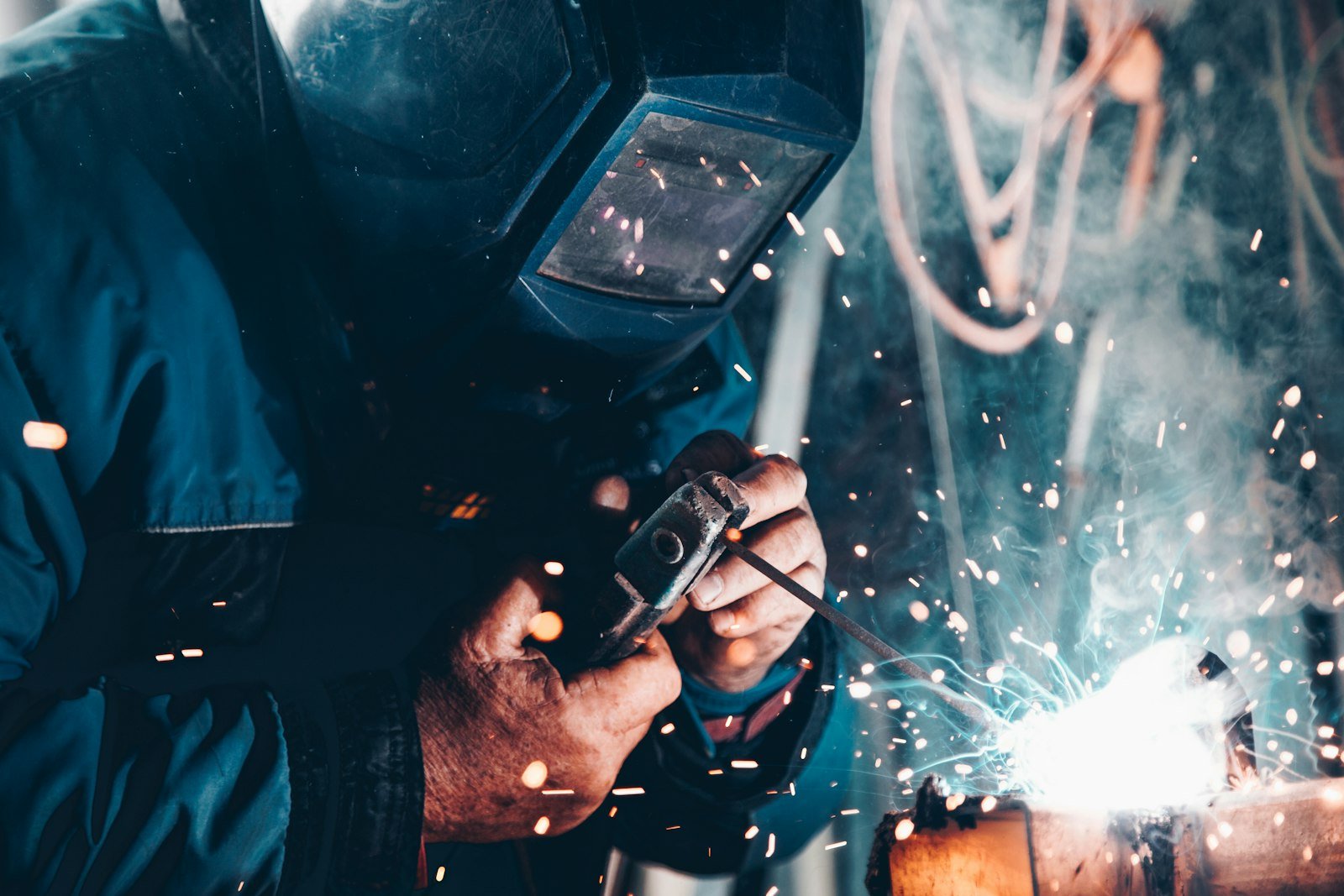 Soldador con equipo de protección trabajando con chispas